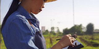 亚洲女农民用便携式平板电脑检查农田里的农机
