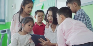 亚洲教师在课堂上使用平板电脑给学生提供在线材料。