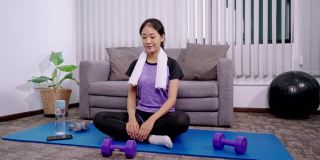 运动女性是穿着运动服坐在家里客厅的垫子上锻炼、健康和生活方式的概念。
