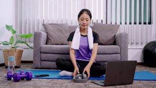 运动女性是穿着运动服坐在家里客厅的垫子上锻炼、健康和生活方式的概念。视频素材模板下载
