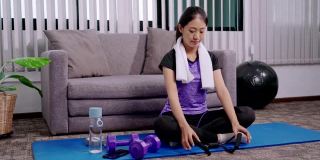 运动女性是穿着运动服坐在家里客厅的垫子上锻炼、健康和生活方式的概念。