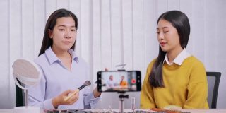 年轻的亚洲女性制作视频，为自己的博客上的化妆品现在的产品和直播视频到社交网络通过互联网在家庭美容博客的概念