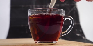 在一个透明的杯子里用甜品勺泡一个红茶包