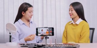 年轻的亚洲女性制作视频，为自己的博客上的化妆品现在的产品和直播视频到社交网络通过互联网在家庭美容博客的概念