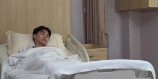 年轻的亚洲医生和护士在医院医务室的病床上用听诊器检查男病人的心肺