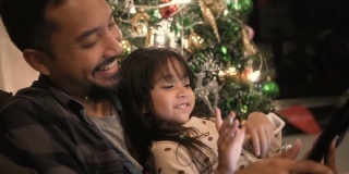父亲和女儿在平板电脑上给朋友和父母写圣诞祝福。