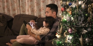 父亲和女儿在平板电脑上给朋友和父母写圣诞祝福。