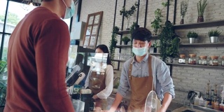 亚洲顾客戴着防护面具在咖啡馆排队等候付款和买咖啡