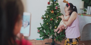 可爱的小女孩在圣诞节期间用手机视频打电话给奶奶