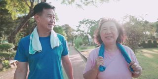 亚洲老年夫妇一起在边娱乐公园散步，健康的退休生活方式，关系目标，幸福微笑的中年夫妇锻炼，家庭户外活动在阳光明媚的日子