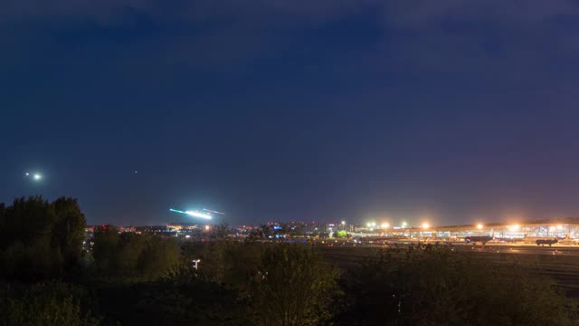 间隔拍摄。北京首都国际机场夜间航站楼，飞机降落，中国。