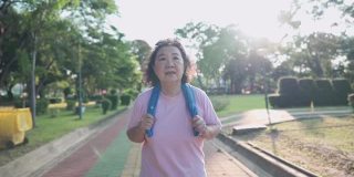 亚洲资深妇女慢跑公园在一个阳光明媚的日子在慢镜头。退休健康生活活动