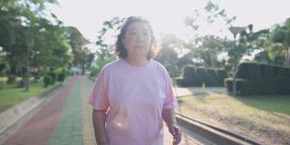 亚洲肥胖老太太在一个阳光明媚的早晨在公园里慢跑，退休健康的生活活动。老年保健，卡路里饮食控制，超重女士跑步，对抗癌症，鼓励人们
