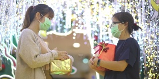 亚洲妇女戴着防护面具在商场的圣诞活动中交换礼物