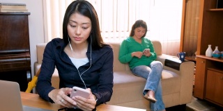 年轻美丽的亚洲女人使用智能手机和工作与笔记本电脑