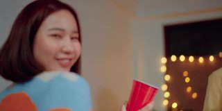 快乐的亚洲朋友在家里跳舞喝酒。