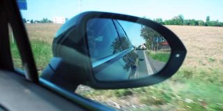 一辆在路上行驶的汽车的近距离后视镜。