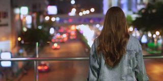 微笑的年轻美丽的亚洲女性游客走在城市的夜晚，看着路灯照明。快乐的漂亮女孩享受和享受城市夜生活的乐趣。