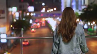微笑的年轻美丽的亚洲女性游客走在城市的夜晚，看着路灯照明。快乐的漂亮女孩享受和享受城市夜生活的乐趣。视频素材模板下载