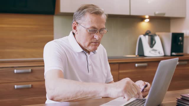 老年人用笔记本电脑购买使用网上网站和银行信用卡预订酒店计划度假，老年人学习支付系统选择服务或产品的互联网概念