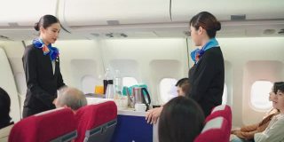 美丽的空姐提供饮料和零食给老乘客在飞机上。