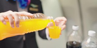 美丽的空姐提供橙汁的年轻乘客在喷气式飞机。
