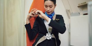 穿着制服的美丽亚洲空姐在飞机上系好安全带。