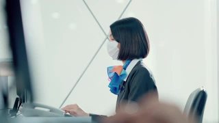 亚洲航空公司女职员在登机台戴上口罩，将护照交给乘客。视频素材模板下载