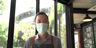在疫情爆发期间，一名戴着口罩的员工正在重新开业，为顾客提供咖啡。