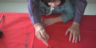 亚洲华人小女孩向她的祖父学习写中国书法