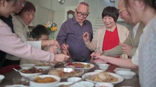 亚洲华人多代家庭庆祝中国新年前夕与传统食物娄桑(生鱼菜肴)团圆饭视频素材模板下载