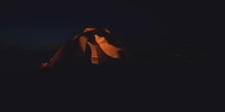 一对浪漫的情侣坐在夜晚的露营帐篷里