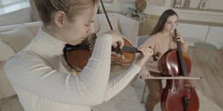 弦乐二重奏的妇女演奏小提琴和大提琴在豪华的家庭室内