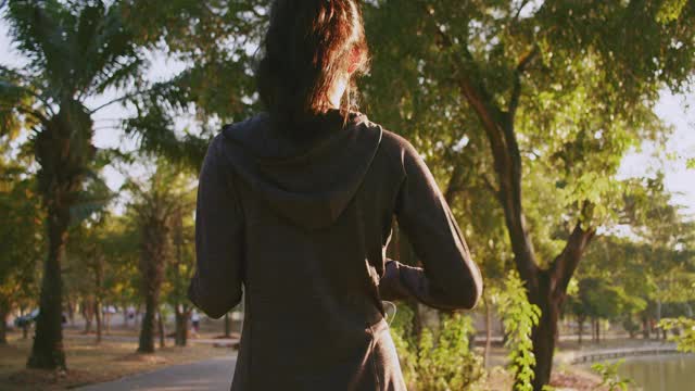 迷人的亚洲少女在公园里跑步。年轻女子晨跑锻炼。