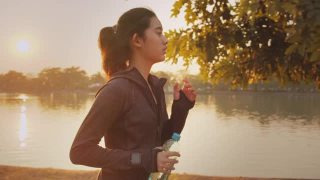 迷人的亚洲少女在公园里跑步。年轻女子晨跑锻炼。视频素材模板下载