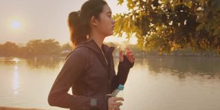 迷人的亚洲少女在公园里跑步。年轻女子晨跑锻炼。