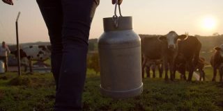 扛着一桶牛奶穿过牧场的农民