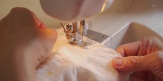 亚洲高级妇女使用缝纫机在家制作婴儿衣服。