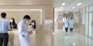 4K宽镜头的大堂等候区在现代化的医院或医疗设施，病人在询问柜台和一组专业医生和护士在医疗中心的卫生服务。