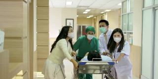 亚洲专业医生与外科医生和病人家属在担架上奔跑和移动昏迷的男性病人通过医院大厅到手术室。医疗保健服务理念。