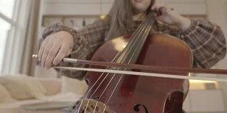 年轻女子音乐家与弓在家中演奏大提琴室内