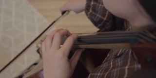 年轻女子音乐家与弓在家中演奏大提琴室内