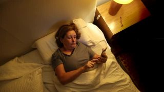 老妇人睡前躺在床上使用智能手机视频素材模板下载