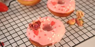 烤架上粉红色的甜甜圈。情人节的概念。女人手里放了一个甜甜圈