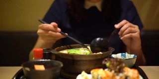 年轻的亚洲女子正在吃一碗日本乌冬