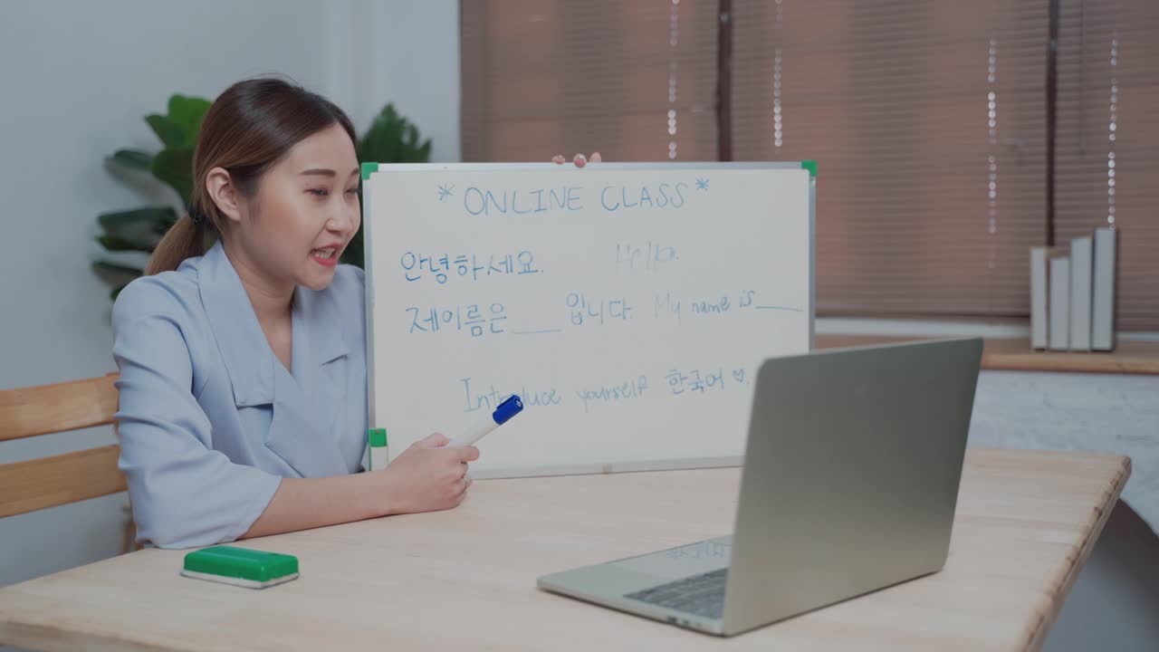 微笑的亚洲女教师使用笔记本电脑远程视频通话教学