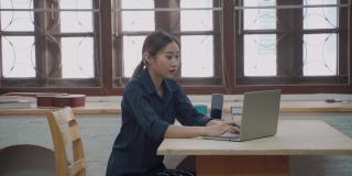 微笑的女商人使用笔记本电脑在公寓工作期间愉快的电话信息