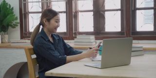 微笑的女商人使用笔记本电脑在公寓工作期间愉快的电话信息