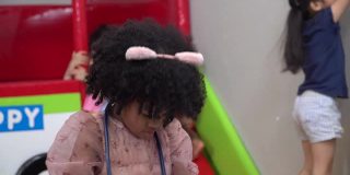 一个非洲裔美国女孩在幼儿园的室内儿童操场上用听诊器扮演医生