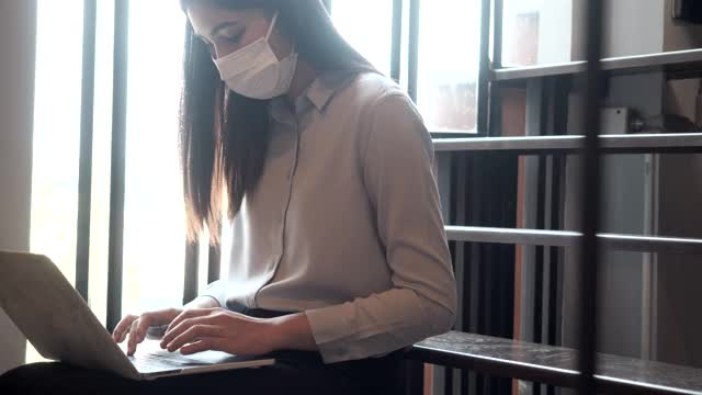 在办公室工作的女性必须一直戴着防护口罩。防止感染的传播。